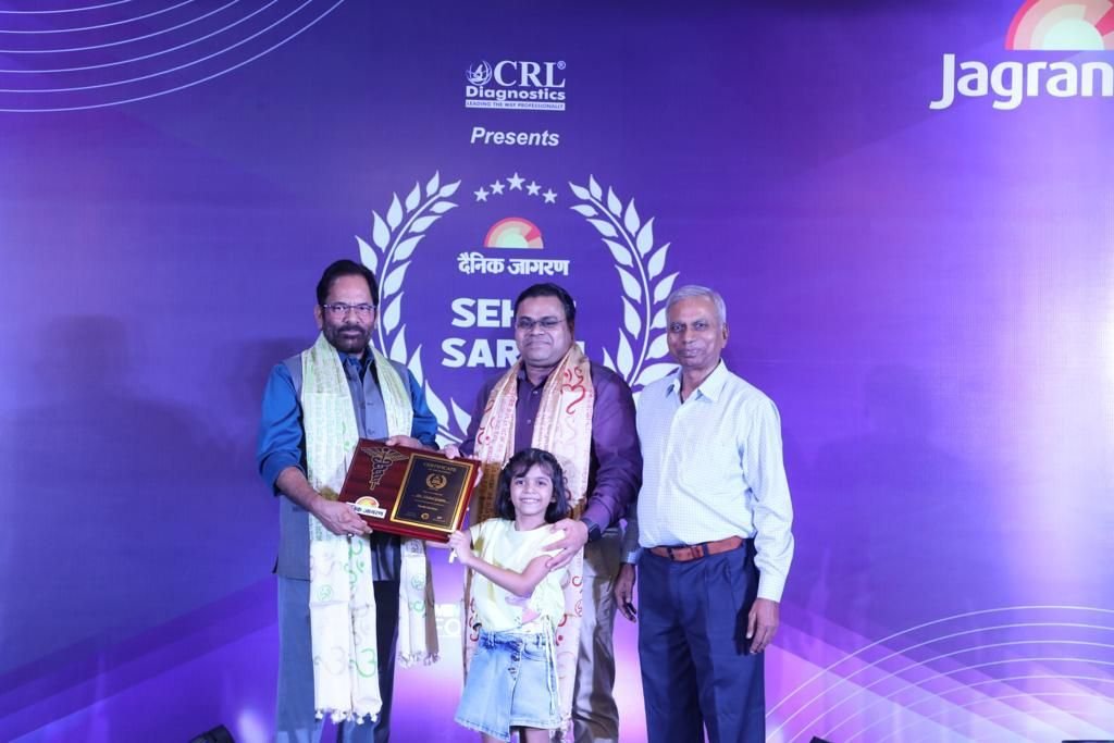 Dr. Vishal Gupta receiving a plaque on stage at a Dainik Jagran event